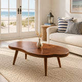 Coastal coffee table with freeform solid wood top and tapered legs in a bright beach room