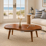 Contemporary coffee table with smooth curves and slim solid wood legs in a beachside room