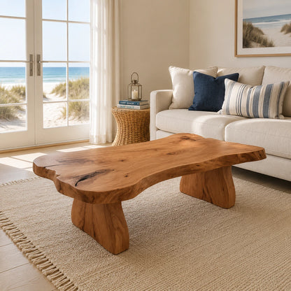 Live edge coffee table with sculpted slab top and broad solid wood legs in a coastal room