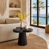 Luxury side table with organic top and sculpted pedestal base beside a modern bed