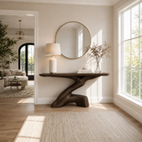 Organic modern console table styled beneath a round mirror in a calm sunlit room