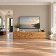 Modern solid wood TV stand with carved coastal scene and low-profile storage design
