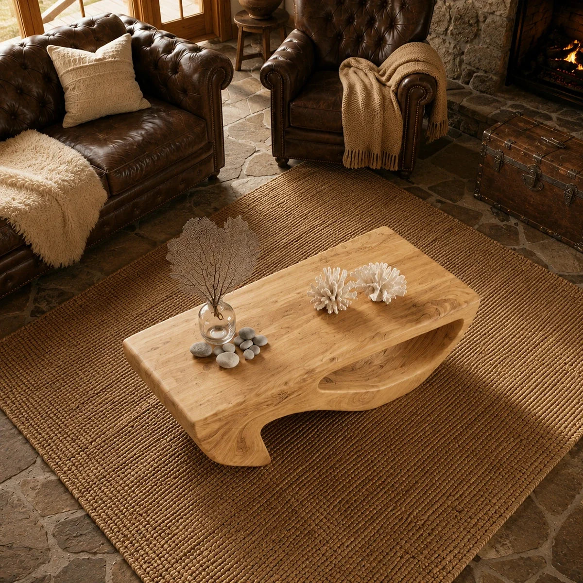 Open sculptural supports give the coffee table an artistic presence near a stone fireplace