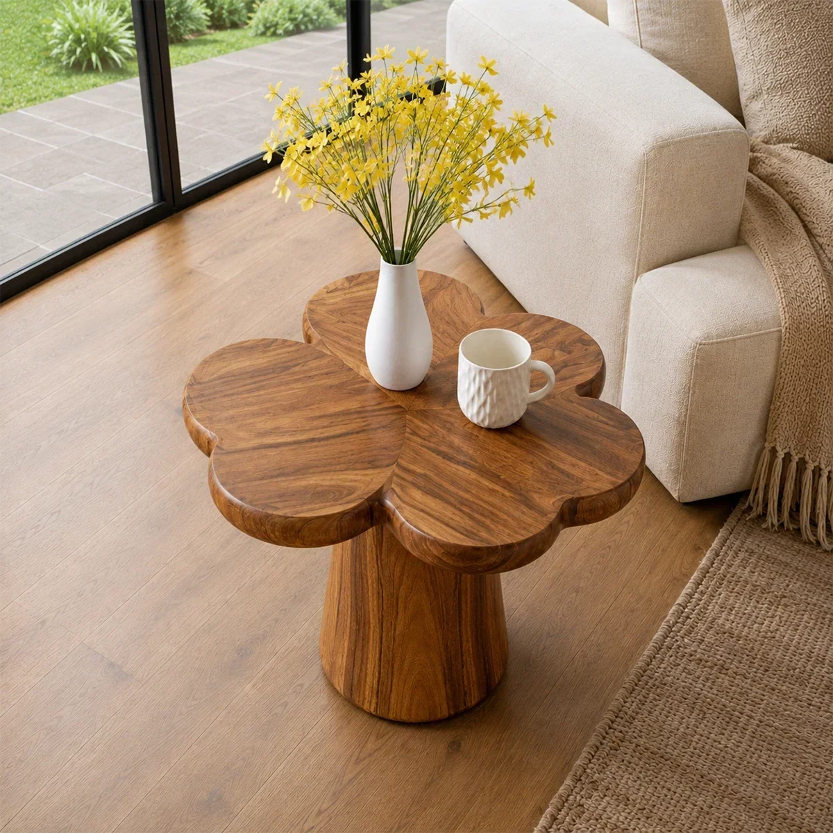 Modern end table with sculpted pedestal form and warm finish beside lounge seating