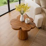 Modern end table with sculpted pedestal form and warm finish beside lounge seating
