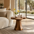 Sculptural end table with clover top and warm wood tone finish in a bright living room