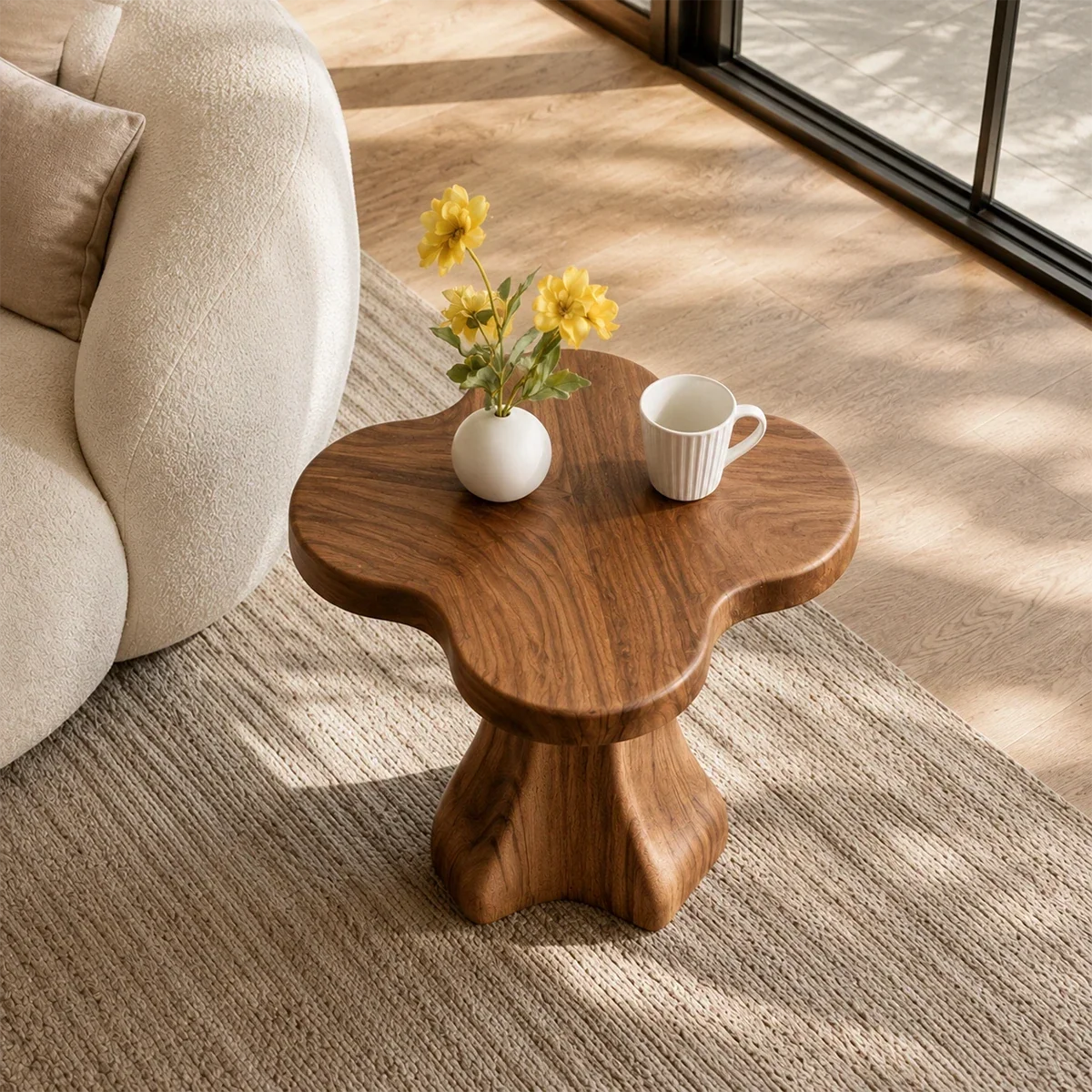 Modern end table with artistic pedestal form and warm finish beside lounge seating