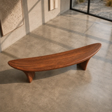 Minimalist bench with clean flowing lines and handcrafted solid wood construction indoors
