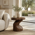 Organic modern side table styled beside a lounge chair in a bright neutral interior