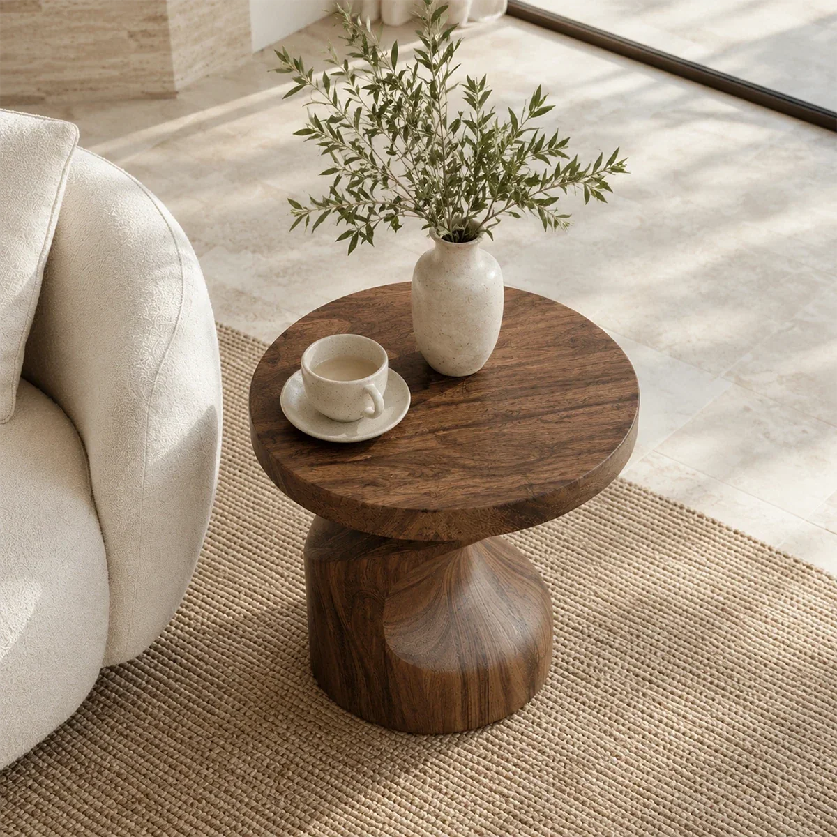 Modern end table with an artistic base and warm dark finish beside soft lounge seating