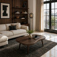 Dark solid wood coffee table with soft curves in a refined modern apartment living room
