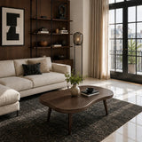 Dark solid wood coffee table with soft curves in a refined modern apartment living room