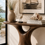 Designer hallway table with sculpted pedestal form and visible grain near ocean views