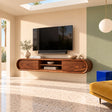 Natural solid wood TV stand with rounded ends and center shelf in a bright room