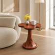 Sculptural end table with petal top and warm wood tone finish in a bright interior