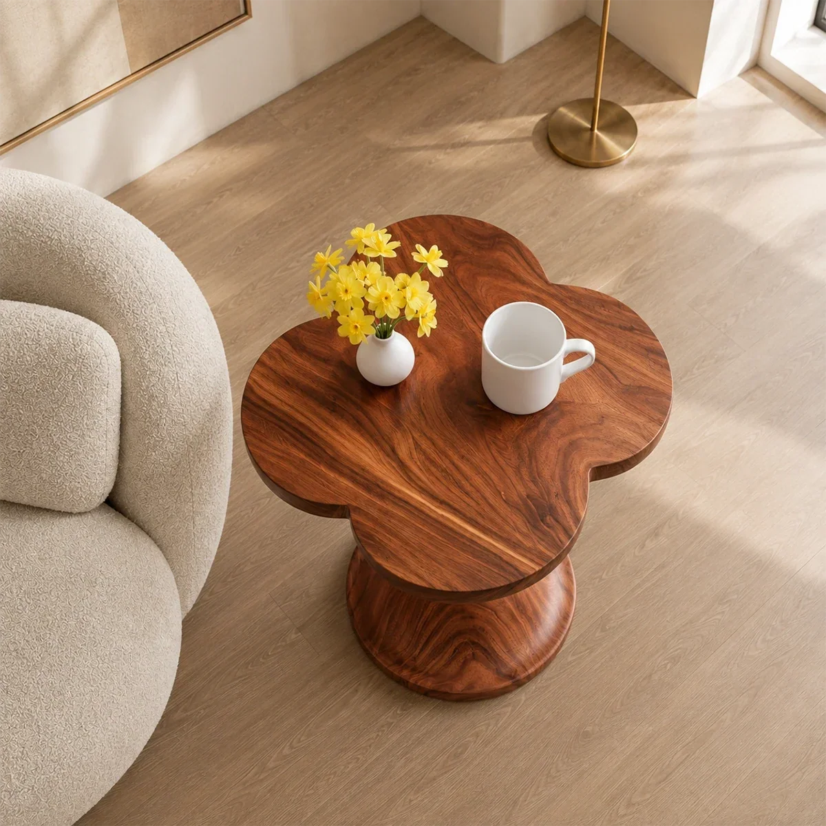 Modern end table with artistic pedestal form and warm finish beside lounge seating