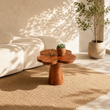 Organic modern side table styled beside curved seating in a calm sunlit interior space