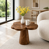 Modern end table with sculpted pedestal form and warm finish beside lounge seating indoors
