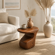 Sculptural end table with flowing base and warm wood tone finish in a bright interior