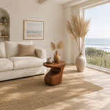 Organic modern side table styled beside soft seating in a calm coastal living room