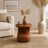 Designer side table with sculpted contours and visible grain in a refined interior