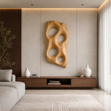 Sculptural wall art with rounded openings creates a bold focal point above a console