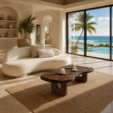 Organic modern coffee table styled on a woven rug in a bright ocean view interior