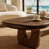Designer coffee table with sculpted legs and visible grain in a sunlit coastal home