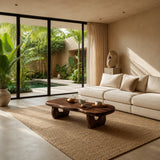 Organic modern coffee table styled on a woven rug beside soft neutral lounge seating