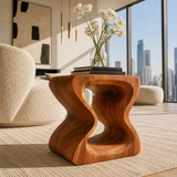 Modern end table with artistic open form and warm finish beside soft lounge seating