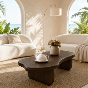 Sculptural coffee table with organic top and dark wood tone finish in a bright room