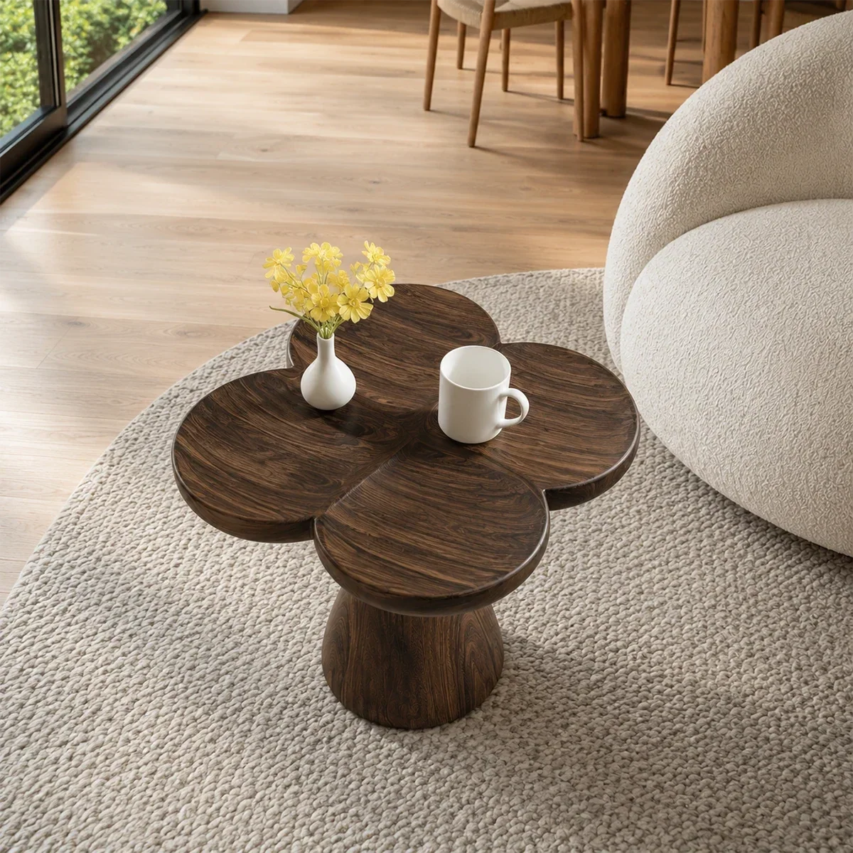 Modern end table with artistic pedestal form and warm finish beside lounge seating indoors
