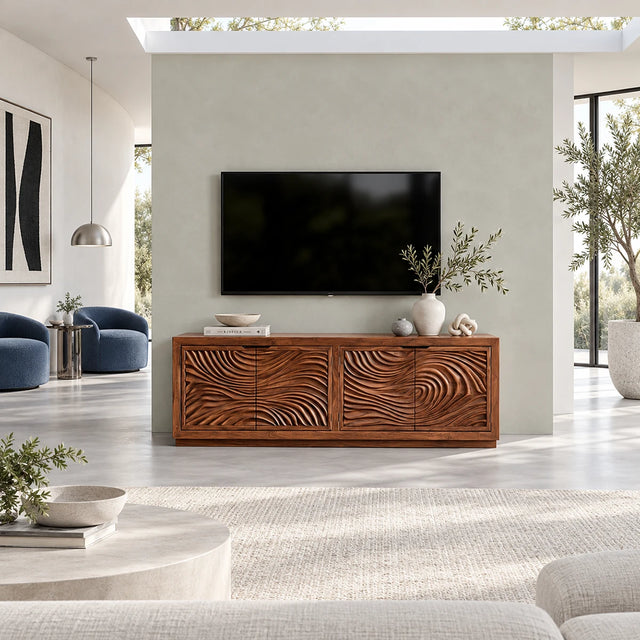 Solid wood TV stand with carved ripple doors and a balanced low profile storage form
