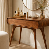 Beauty vanity table featuring a rounded profile and warm finish in a sunlit interior