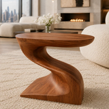 Modern end table with an artistic S shaped base beside soft lounge seating indoors