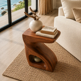 Curved side table adds sculptural form and a small display shelf to serene interiors