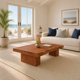 Solid wood coffee table with broad slab top and block legs in a bright coastal living room