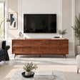 Solid wood TV stand with six drawers, brass ring pulls, and tapered legs below TV
