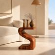 Sculptural end table with sweeping S curve and warm wood tone finish in a bright room