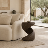 Statement end table with flowing lines and visible grain in a minimalist home setting
