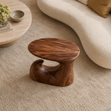 Modern end table with an artistic wave base and warm finish beside lounge seating